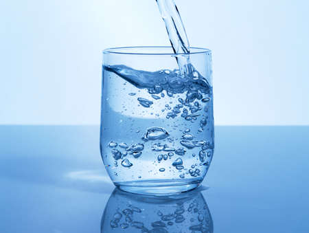 A glass of water can do the world of good. Studio shot of a glass of water being poured in studio.の写真素材