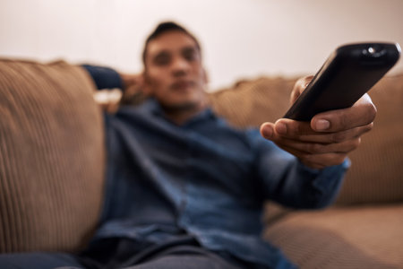 Oh look theyre playing my favourite film. Shot of a young man holding the remote while watching TV.