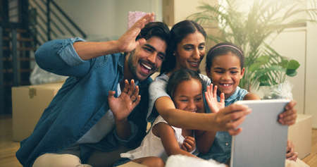 Connecting with family far away. Cropped shot of a young family making a video call on a tablet at...