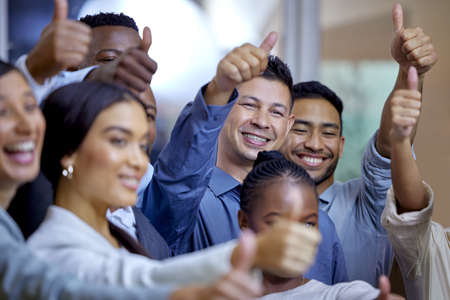 Make it our problem. Shot of a group of businesspeople showing the thumbs up in a modern office.の写真素材