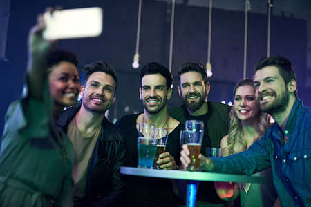 Remembering an awesome night out. Shot of a group of young friends taking a selfie together while...