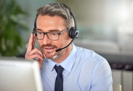 No dreams truly runs cold. Shot of a mature man using a headset and talking to clients while using...