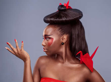 Theres a lot to learn about other cultures. Studio shot of a beautiful young woman wearing Asian inspired makeup and posing with origami against a grey background.の写真素材