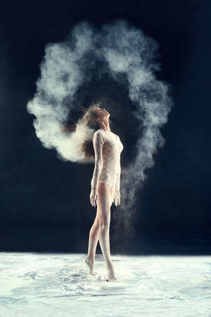 Studio muse. Studio shot of a young woman leaving a trail of powder in the air by whipping her hair.の写真素材