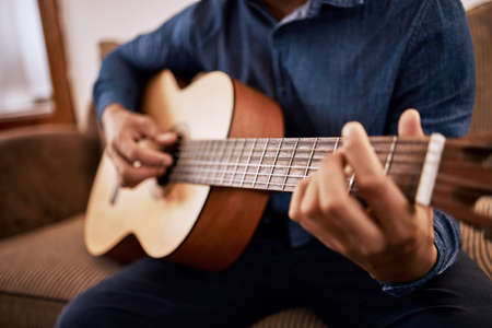 Time to tune up these skills. Shot of a man practicing his guitar skills at home.の写真素材