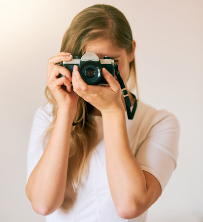 Freezing this moment in time. Shot of an unrecognizable young woman taking a photo with her camera at home.の写真素材
