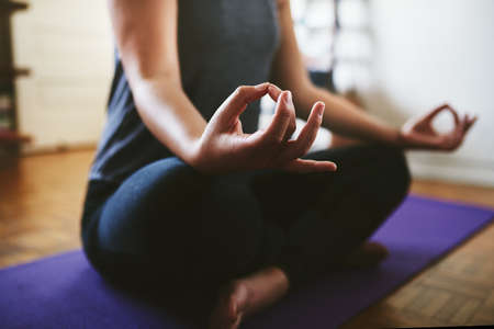 Finding my balance. Cropped shot of an unrecognizable woman sitting on a yoga mat and meditating...