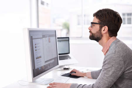 Hes on the project. A handsome young man at his desk in an office.の写真素材