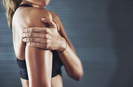 It hurts but the workout was worth it. Shot of a sportswoman with a shoulder injury.の写真素材