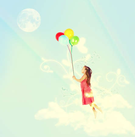 Floating away. A young girl being lifted in the air by a bunch of colorful balloons.の写真素材