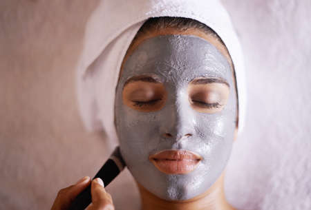 Pampering her skin with a facial treatment. Shot of a young woman enjoying a facial treatment at a spa.の写真素材