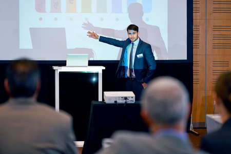 Making presenting look good. A handsome businessman gesturing while giving a presentation at a press...