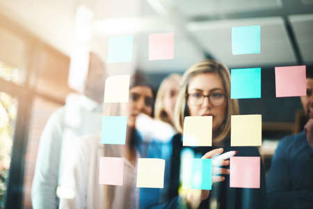 Marketing ideas that match the company brand. Shot of a group of businesspeople arranging sticky...