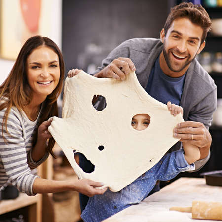 Look, a dough monster. Portrait of a happy family being playful with the pizza dough they made.