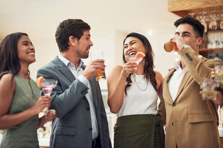 A little alcohol is never a bad idea. Cropped shot of a group of young friends enjoying alcoholic drinks in a bar.の写真素材