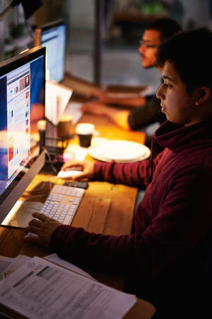 Getting the job done. Cropped shot of a group of young coworkers working in a dimly-lit office.