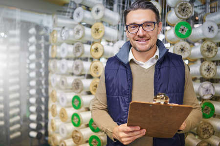 Inventory is done. Portrait of a manager holding a clipboard while standing in front of wire spools...