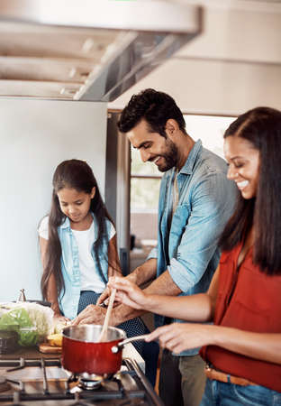 Time to cook, time to bond. Shot of a happy young family preparing a meal in the kitchen together at...