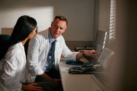 Showing her the ropes. Cropped shot of doctors working late into the night.の写真素材