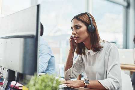 I am ready to answer all your questions. Shot of a focussed young businesswoman wearing a headset...