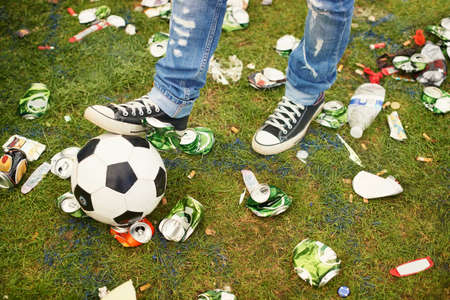 Kicking around in the aftermath. A person playing with a football amidst the trash left behind at a music festival.の写真素材