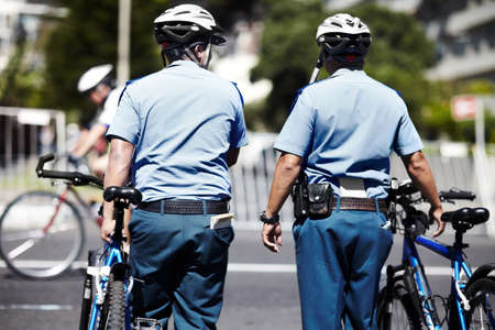 Event security. A cropped rear view shot of two policemen standing with their bicycles.の写真素材