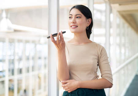 Tedious jobs can be streamlined and simplified with technology. Shot of a young businesswoman using a cellphone in an office.の写真素材