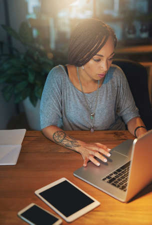 Shes got deadlines to meet. Cropped shot of a young woman working late in the office.の写真素材