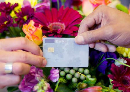 Who says beauty cant be bought. Cropped shot of a woman buying flowers with her credit card from a...