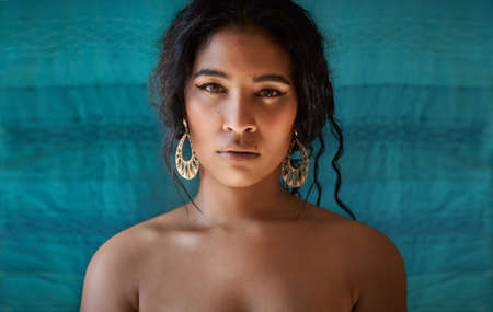 There is beauty in simplicity. Cropped shot of a beautiful young woman against a blue background.の写真素材