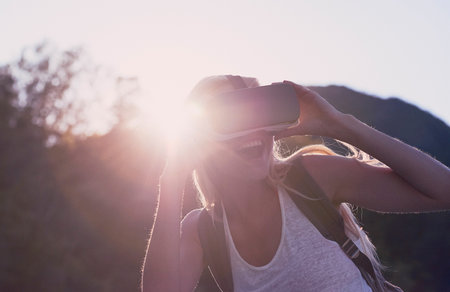 Excited young woman on holiday using VR headset. Young woman on holiday excited about using VR...