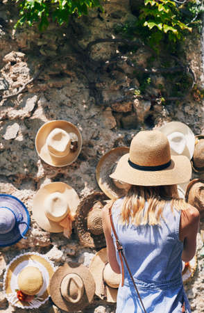 Woman shopping for hats in Italy on summer vacation. Rear view of woman exploring town in Italyの写真素材