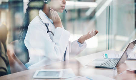 Closeup african american woman doctor using her laptop to do an online remote consult while sitting...