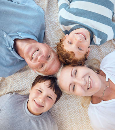 Happy caucasian grandparents lying with grandsons on a beach. Adorable, happy, children bonding with grandmother and grandfather in a garden or park outside. Family taking selfies togetherの写真素材