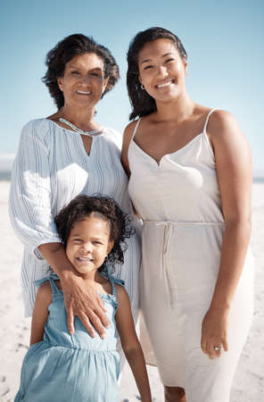 Smiling mixed race family standing together on a beach. Happy hispanic grandmother bonding with...