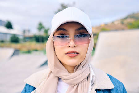 Beautiful young arab woman posing outdoors in a headscarf. Attractive female muslim wearing a hijab posing outside. Shes all about style and fashion. Mixed race woman looking confident and trendyの写真素材