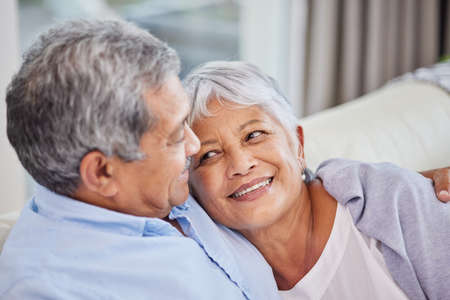 Closeup of an affectionate mixed race senior couple relaxing in their living room at home. Hispanic...