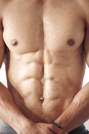 Closeup of one fit topless mixed race man with muscular hard six pack abs from regular exercise in a...