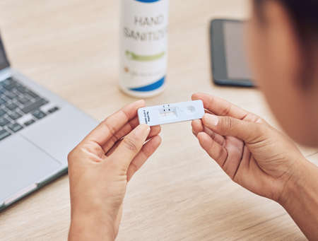 Closeup shot of a mixed race unrecognizable woman holding a rapid test kit. Female office worker...