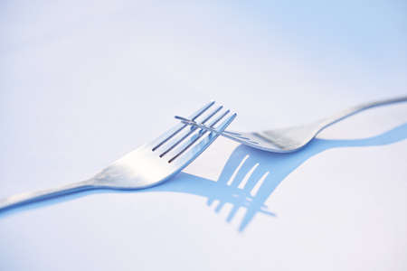 Two forks joined together symbolising togetherness, dependance and unity. This is a symbol of teamwork, relationship and partnership issues and troubles, or dependencies between countries or companiesの写真素材