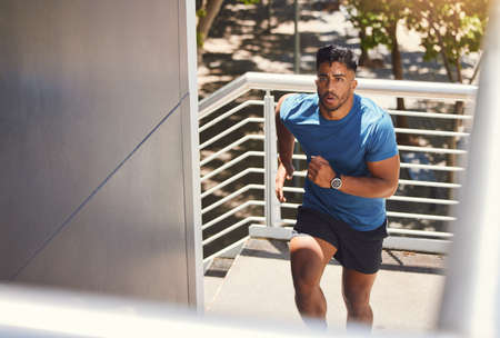 Handsome mixed race athletic man running up the steps on of a building while focused on his fitness....