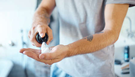 An unknown man applying shaving foam to his face in a bathroom at home. One unrecognizable male...