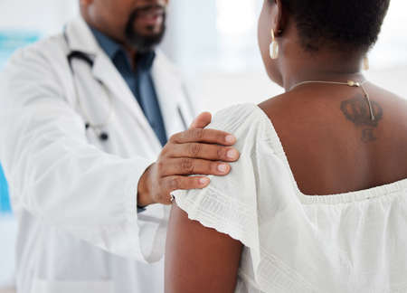 Doctor touching a patient on the shoulder in support. Closeup on hand of doctor being kind to a patient in a checkup. Medical gp offering a patient comfort during a consult cropped.の写真素材