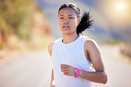 Active mixed race young woman running for exercise outdoors. Athlete jogging for a refreshing cardio...