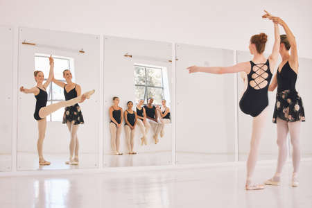 Young woman dance instructor teaching a ballet class to a group of a children in her studio....