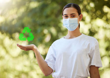 Closeup of a beautiful young woman in a mask holding copyspace showing a recycle sign. Depicting the...