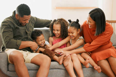 A happy mixed race family of five relaxing on the sofa at home. Loving black family being playful on...