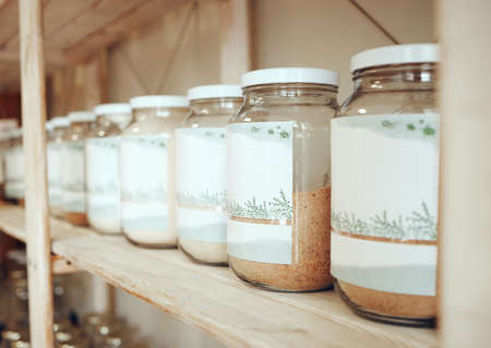 Glass jars of spices lined up in a row on a display shelf in a grocery store. Fresh produce from the farmers market. Get to your local green grocer for all your cooking, spice and flavouring needsの写真素材