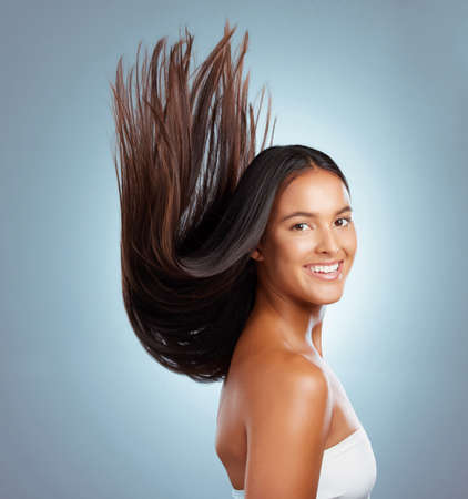 Portrait of a hispanic brunette woman with long lush beautiful hair smiling and posing against a...