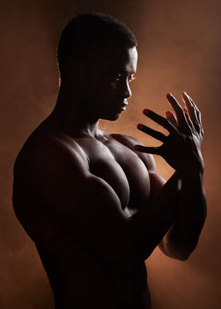 A handsome, muscular young african american man in studio against a dark background. A macho male athlete looking thoughtful isolated on black. Exercising body and mind. A question of mental healthの写真素材